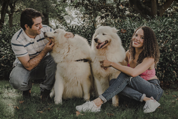 Casal brincando com seus dois cães no parque